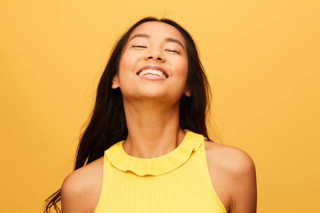 woman wearing yellow smiling facing upwards
