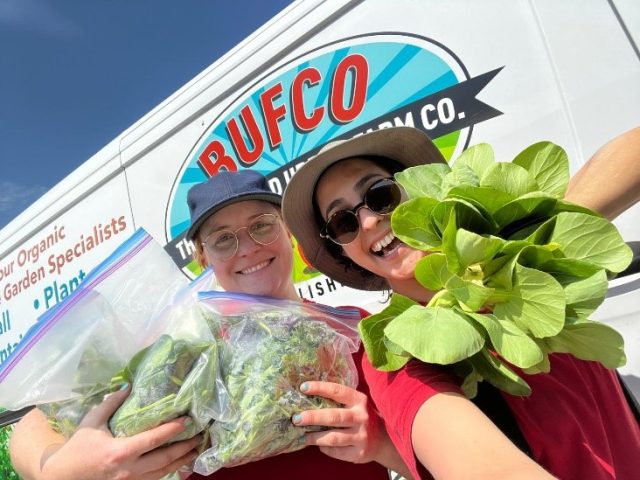 two people holding garden fresh veggies